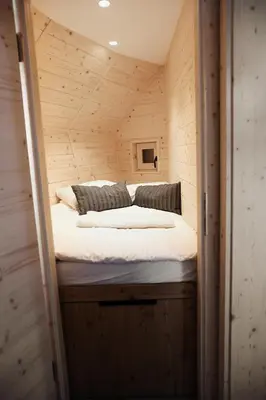 a bed in a small room in a wooden cabin at Chalet Velika Planina with Sauna - I FEEL ALPS in Stahovica