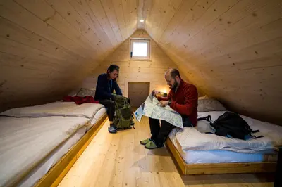 two men sitting in a attic room with two beds at Chalet Velika Planina with Sauna - I FEEL ALPS in Stahovica