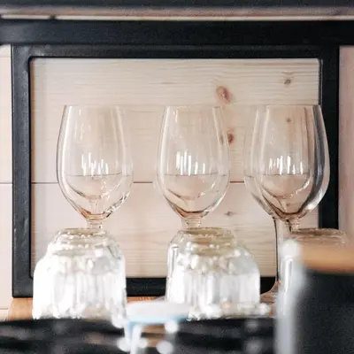 three wine glasses sitting on a table in front of a microwave at Chalet Velika Planina with Sauna - I FEEL ALPS in Stahovica