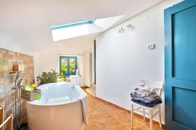 a bathroom with a white tub and a blue door at Apartma Hiša Pliska in Pliskovica