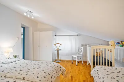 a white bedroom with two beds and a crib at Apartma Hiša Pliska in Pliskovica