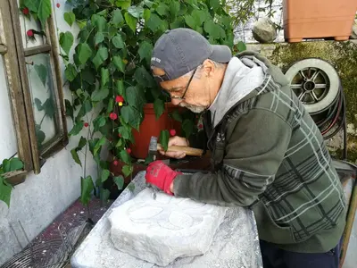 an older man is working on a piece of paper at Apartma Hiša Pliska in Pliskovica