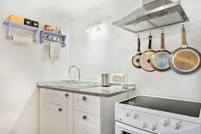 a kitchen with white cabinets and a sink and pots and pans at Apartma Hiša Pliska in Pliskovica