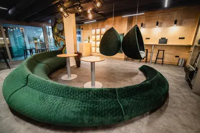 a green couch in a room with tables and chairs at Dragons Dream Hostel in Ljubljana