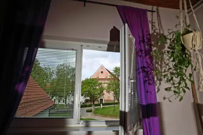 a view of a church from a window with purple curtains at House Minka in Ptuj