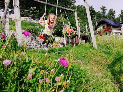 two young girls playing on a swing in a garden at Vineyard cottage Podržaj in Otočec