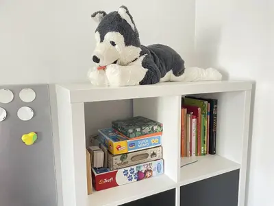 a stuffed cow is sitting on top of a book shelf at Apartment Ljubljana in Ljubljana