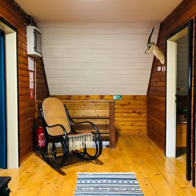 a room with a rocking chair in a room with a wall at Red Beech Cabin - An Alpine Cabin near Lake Bohinj in Bohinj