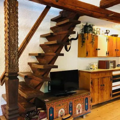 a living room with a wooden staircase and a television at Red Beech Cabin - An Alpine Cabin near Lake Bohinj in Bohinj