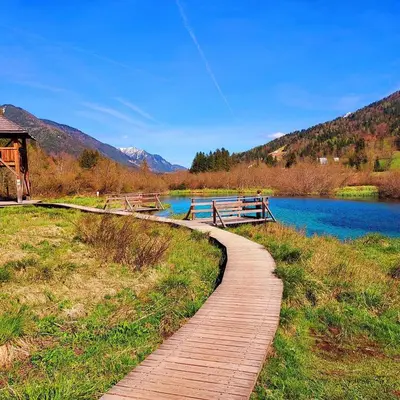 a wooden path next to a river with a mountain at Villa Nebina in Rateče