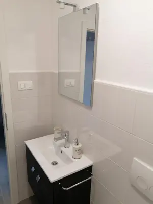 a white bathroom with a sink and a mirror at Apartments Rosemary Ljubljana & Free Parking in Ljubljana