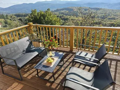 a deck with chairs and a table with a view at Vineyard cottage Stopar in Straža