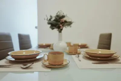 a table with plates and cups and a vase with flowers at Apartments Pr' Štormanu in Kanal