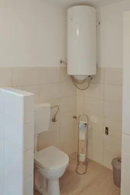 a small bathroom with a toilet and a tank at Apartments Pr' Štormanu in Kanal