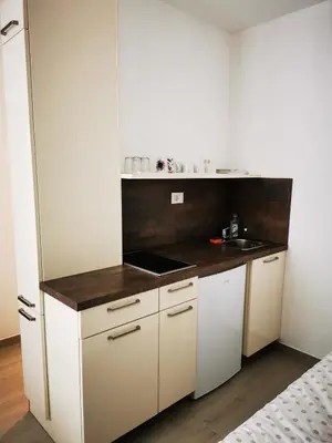 a small kitchen with white cabinets and a sink at Apartments Pr' Štormanu in Kanal
