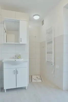 a white bathroom with a sink and a mirror at Apartments Pr' Štormanu in Kanal