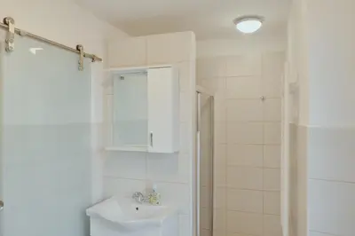 a white bathroom with a sink and a shower at Apartments Pr' Štormanu in Kanal
