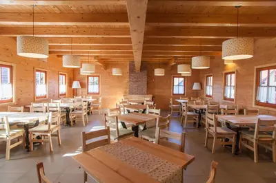 a restaurant with wooden tables and chairs and windows at Wine & Tourism Bračko in Jakobski Dol