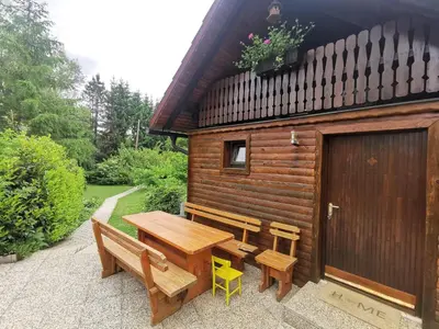 a wooden cabin with a wooden table and benches at Wooden Cabin Zurej with Hot Tub in Bukovje v Babni Gori