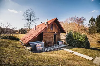 a small wooden cabin with a porch on a field at Wooden Cabin Zurej with Hot Tub in Bukovje v Babni Gori