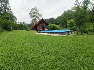 a house with a swimming pool in the middle of a field at Wooden Cabin Zurej with Hot Tub in Bukovje v Babni Gori