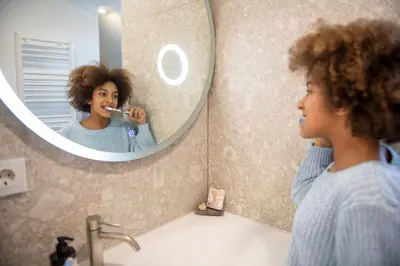 a woman brushing her teeth in front of a mirror at Emerald Valley Apartments in Bovec