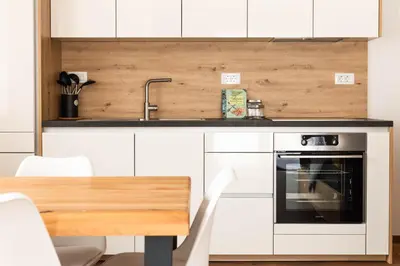a kitchen with white cabinets and a sink and an oven at HIŠA KOSOBRIN in Kranjska Gora