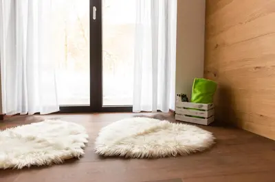 two white furry rugs in a room with a window at HIŠA KOSOBRIN in Kranjska Gora