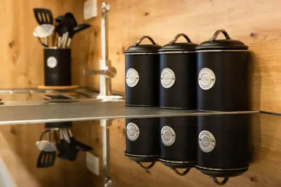 four black containers sitting on a counter in a kitchen at HIŠA KOSOBRIN in Kranjska Gora