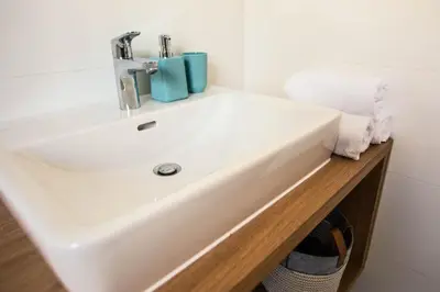 a white bathroom sink with a blue cup on it at HIŠA KOSOBRIN in Kranjska Gora