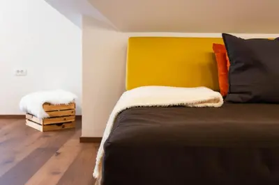a bed with a yellow headboard in a room at HIŠA KOSOBRIN in Kranjska Gora