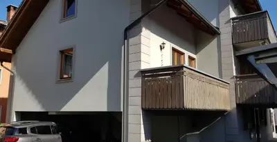 a house with a balcony and a car parked next to it at 7 LAKES apartment in Bohinj