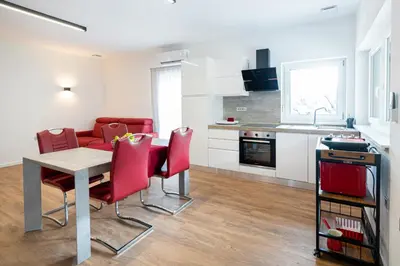 a kitchen and dining room with a table and red chairs at Hiša Kragelj in Most na Soči