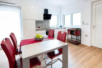 a kitchen with a table and some red chairs at Hiša Kragelj in Most na Soči