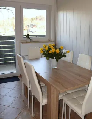 a dining room table with chairs and a vase of flowers at M&M Apartment in Zgornje Gorje