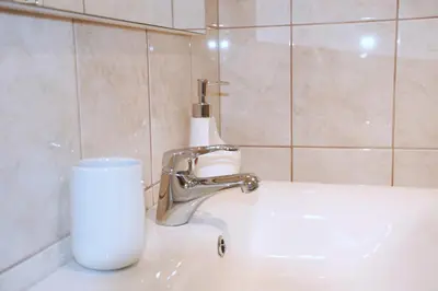 a bathroom sink with a faucet and a cup at M&M Apartment in Zgornje Gorje