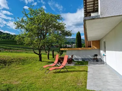 two chairs sitting on the grass next to a building at M&M Apartment in Zgornje Gorje