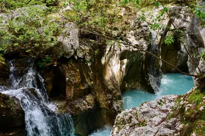 a waterfall in a rocky canyon with blue water at Apartment DOMI in Soča
