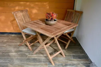 a wooden table with two chairs and a vase with flowers on it at Rustic Apartment PETRA in Soča