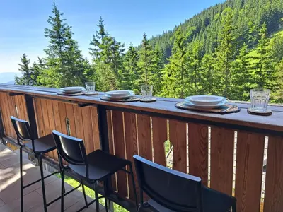a table on a deck with a view of the mountains at Golte SkiCenter App MOUNTAIN VIEW WITH BALCONY in Mozirje