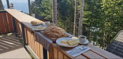 a breakfast of bread and cheese on a table on a balcony at Golte SkiCenter App MOUNTAIN VIEW WITH BALCONY in Mozirje