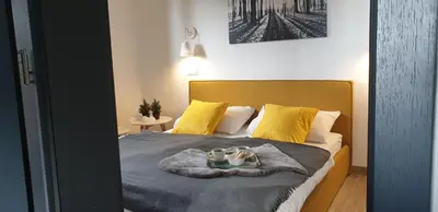 a bedroom with a bed with yellow pillows and a blanket at Golte SkiCenter App MOUNTAIN VIEW WITH BALCONY in Mozirje