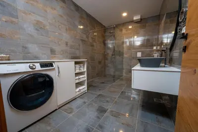 a washing machine in a bathroom with a shower at Cirus apartments in Kočevje