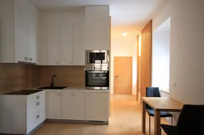 a kitchen with white cabinets and a wooden table at Cirus apartments in Kočevje