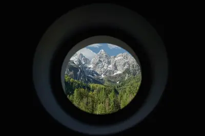 a view of a mountain through a round window at Triangel Boutique Hotel in Kranjska Gora