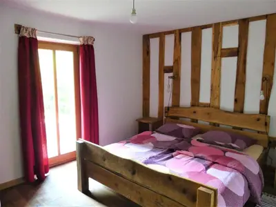 a bedroom with a large wooden bed with red curtains at Hiša ob potoku in Avče