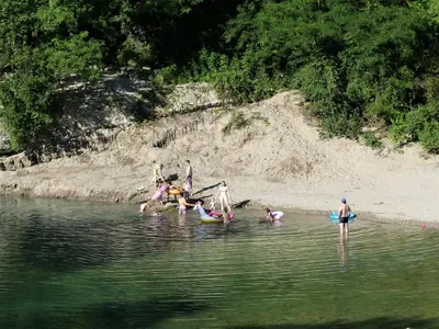 a group of people in the water at a beach at Hiša ob potoku in Avče