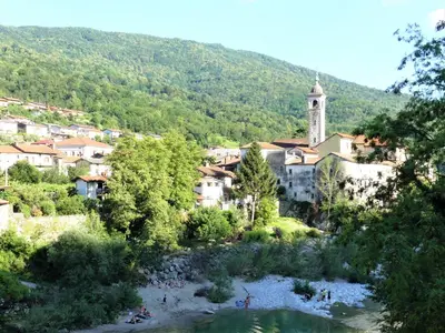 a town with a river in front of a village at Hiša ob potoku in Avče