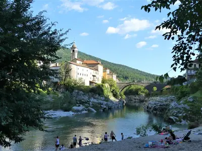 a group of people on a river with a bridge at Hiša ob potoku in Avče