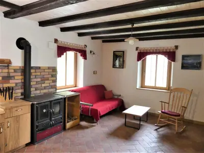 a living room with a red couch and a stove at Hiša ob potoku in Avče